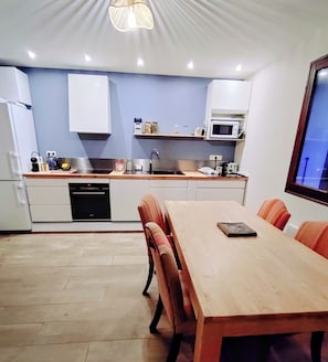 A modern kitchen with white cabinets, a wooden dining table, and orange chairs. - Welcome to Skimoon! Our family chalet with panoramic view of Haut Verdon valley (Villars-Colmars)
