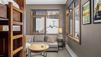 Una habitación acogedora con un sofá, una mesa redonda y una ventana con vistas a un paisaje nevado.