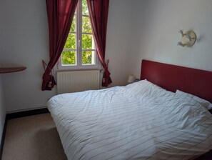 A bedroom with a bed, a window with curtains, a radiator, and a wall-mounted light fixture. - Figarol Cabin (Ground Floor - Pic de Paloumère) (Figarol)
