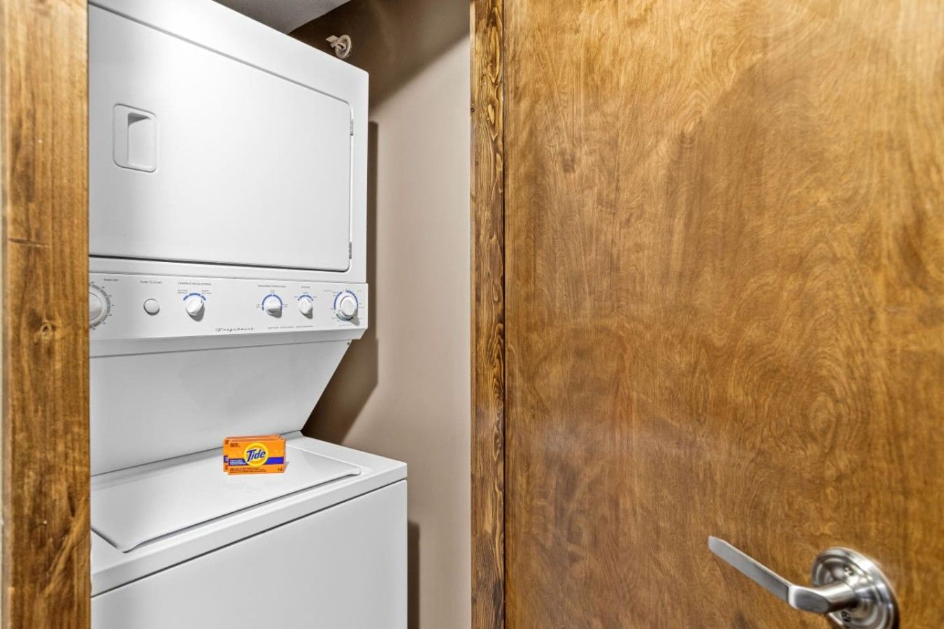 A white laundry machine with Tide detergent in a wooden door frame.