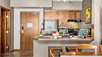 Una cocina moderna con armarios de madera, un refrigerador integrado y una zona de comedor con mesa y sillas.