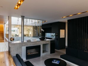 A modern living room with a fireplace, a glass wall, and a black sofa. - Venice Beach House (Los Angeles)