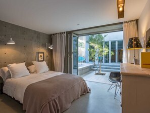 A modern bedroom with a large bed, a desk, and a view of the outdoors. - Venice Beach House (Los Angeles)