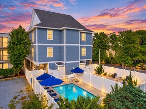 Ein zweistöckiges Haus mit Swimmingpool, Außenbereich zum Sitzen und einem umzäunten Garten.