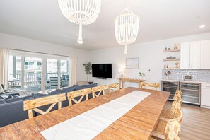 Ein modernes Wohnzimmer mit einem großen Esstisch aus Holz, einer Couch und einem Fernseher.