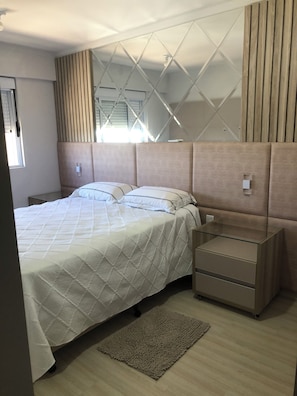 A modern bedroom with a bed, bedside tables, and a mirror.