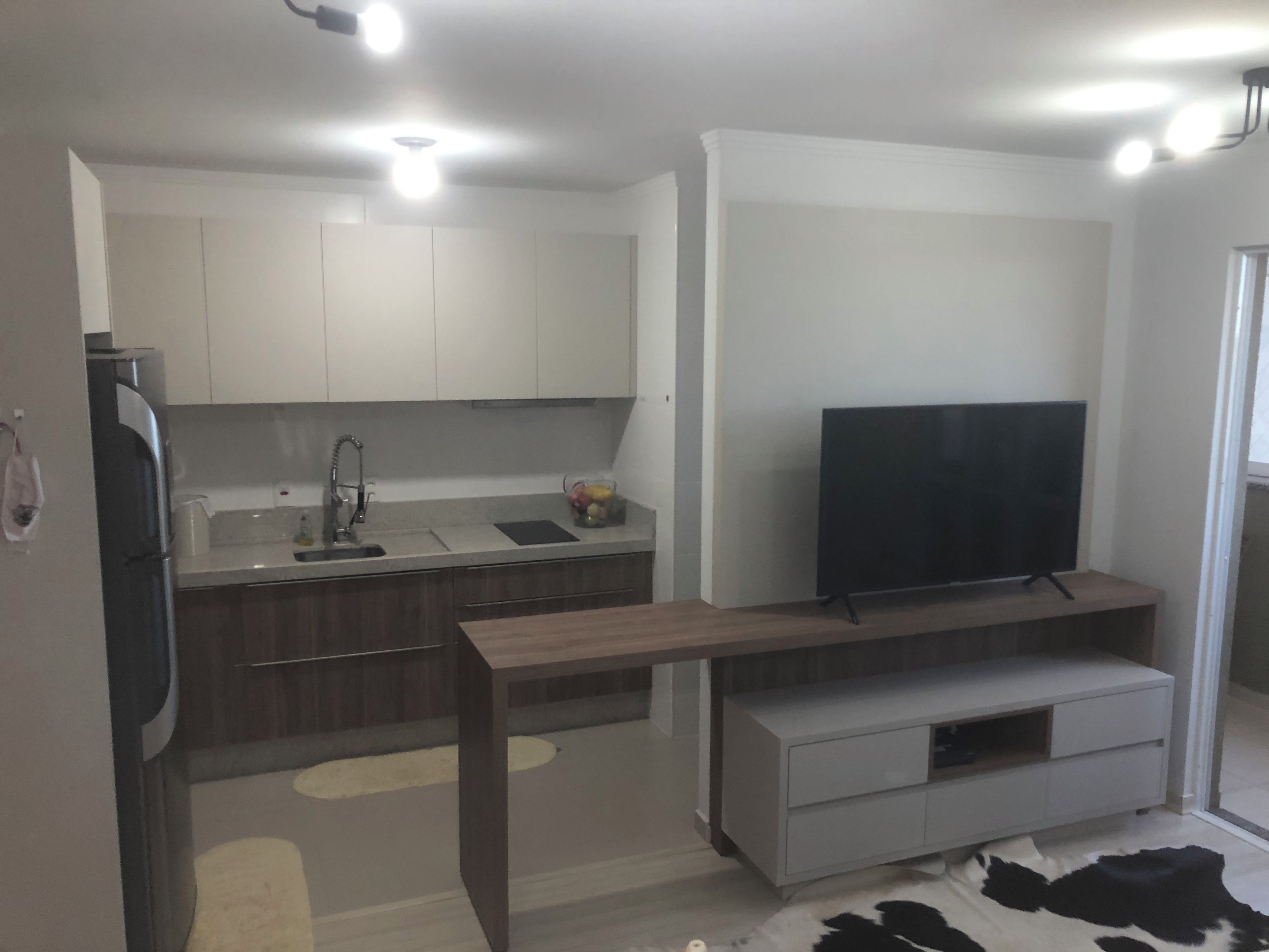 Een moderne keuken met een ingebouwde televisie, een eethoek met een houten tafel, en een keukeneiland met een spoelbak.