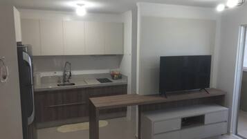 Een moderne keuken met een ingebouwde televisie, een eethoek met een houten tafel, en een keukeneiland met een spoelbak.