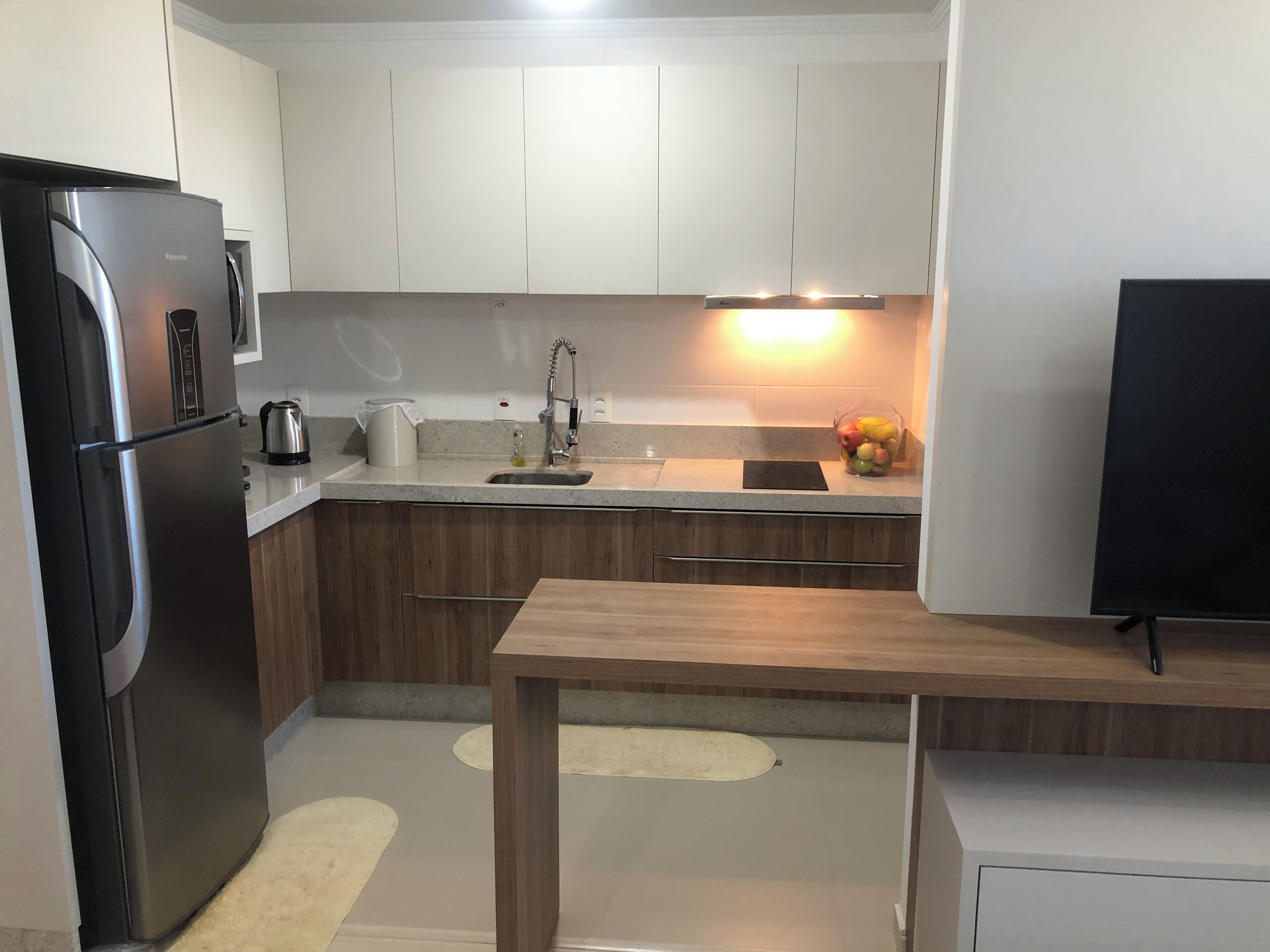 A modern kitchen with a refrigerator, sink, and wooden cabinets.