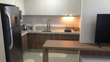 A modern kitchen with a refrigerator, sink, and wooden cabinets.
