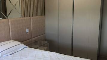 A bedroom with a bed, a bedside table, a mirror, and a wardrobe.