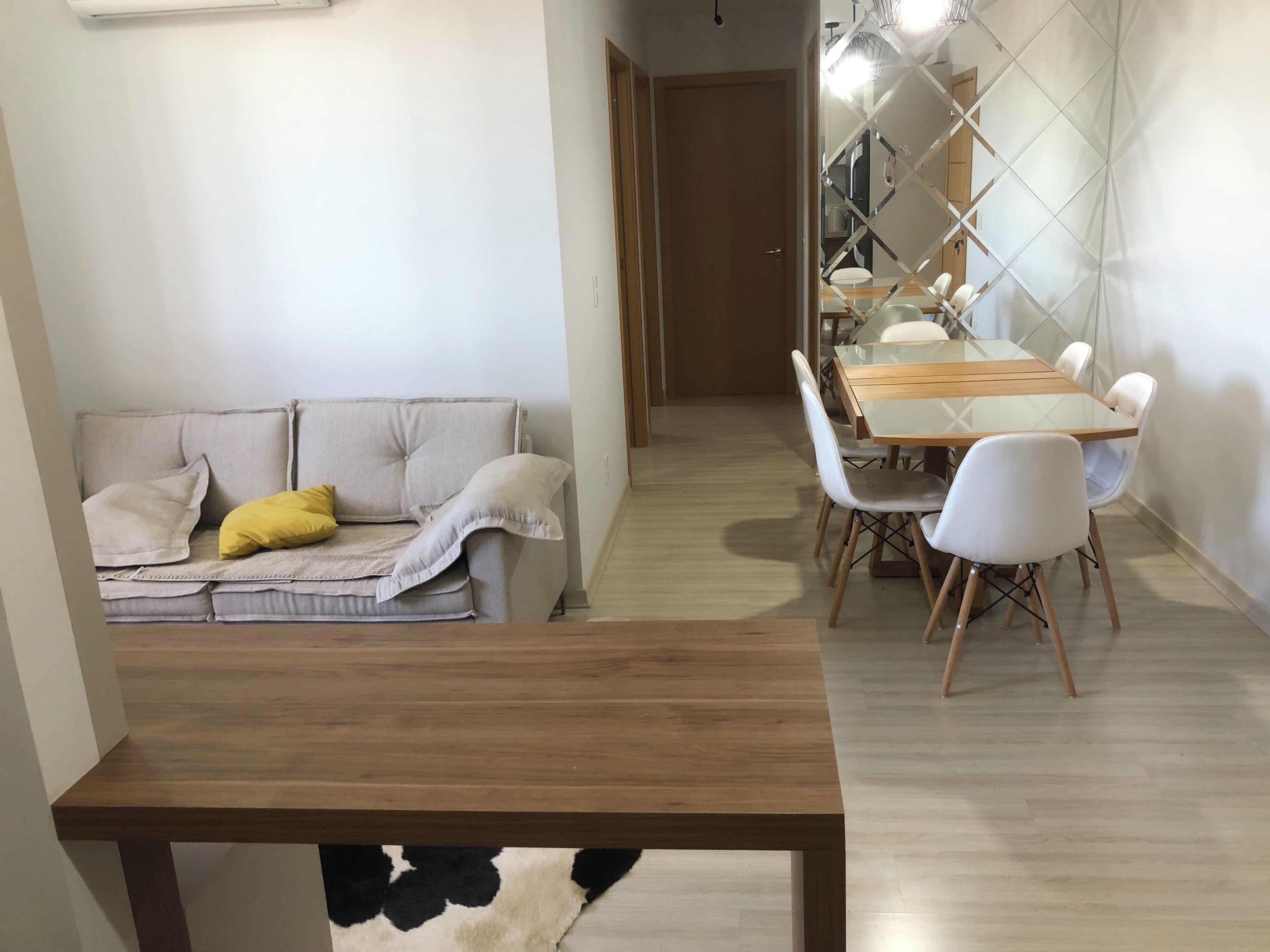 A modern living room with a sofa, a dining table with chairs, and a patterned rug.