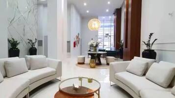 A spacious living area with a modern design, featuring a sofa set, a coffee table, and a dining table with chairs.