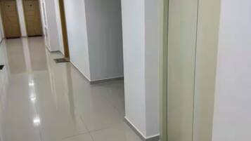 Een schone, goed verlichte gang met een bord dat liftverkeer aangeeft, een betegelde vloer en een deur met een rookverbodsdeken.