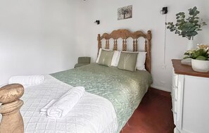 A neatly made bed with a green bedspread and white pillows, a wooden headboard, a bedside table with a lamp, and a potted plant on a dresser. - Lovely apartment in Pont-Audemer with WiFi (Pont-Audemer)