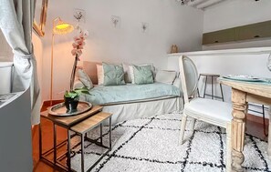 A cozy room with a bed, a dining table, and a chair. There's a potted plant on a side table and a lamp on the floor. - Lovely apartment in Pont-Audemer with WiFi (Pont-Audemer)