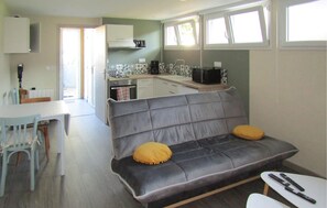 Ein kompakter Wohnbereich mit einer Couch, einem Esstisch und einer Küchenzeile.