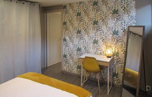 A hotel room with a bed, a desk with a chair, a lamp, and a mirror. - 1 bedroom beautiful apartment in AGNEAUX (AGNEAUX)