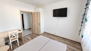A bedroom with a bed, a desk, a chair, a wardrobe, and a TV mounted on the wall. - Komfortný 3 izbový byt pri centre s parkovaním (Liptovský Mikuláš)