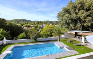 Une piscine offrant une vue sur un village et des collines en arrière-plan.