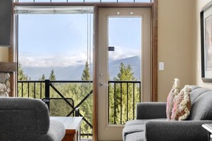 Una habitació amb una porta corredissa de vidre que dona a un balcó amb vista a la muntanya.