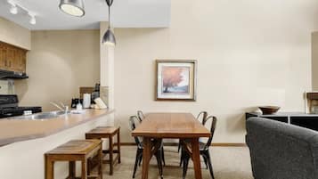 A kitchen with a dining table, chairs, a sofa, and a framed picture on the wall.