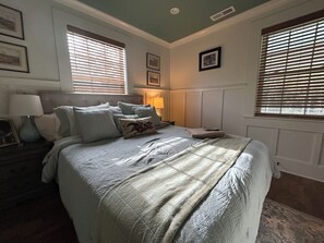 Ein Schlafzimmer mit einem Bett, Nachttischen, einer Lampe und gerahmten Bildern an der Wand.