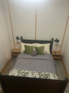 A bedroom with a bed, two bedside tables, and two lamps.