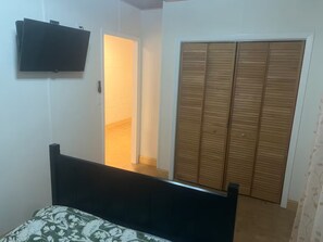 A bedroom with a bed, a TV mounted on the wall, and a wardrobe.
