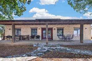 A covered patio area with stone walls, outdoor seating, and a red door. - King Suite Walkable to Wineries + Private Porch (Fredericksburg)