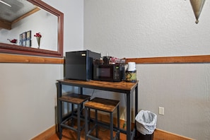 A kitchenette with a refrigerator, microwave, and coffee maker on a wooden table. - King Suite Walkable to Wineries + Private Porch (Fredericksburg)