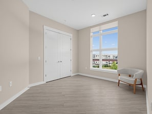A room with a large window, a white door, and a chair. - Brand-new Luxury Furnished Penthouse in Noda 30 Night Mid-term Rental (Charlotte)