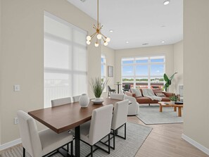 A modern living room with a dining area, large windows, and a view of the outdoors. - Brand-new Luxury Furnished Penthouse in Noda 30 Night Mid-term Rental (Charlotte)