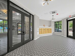 A modern lobby with a patterned floor, glass doors, a reception desk, and lockers. - Brand-new Luxury Furnished Penthouse in Noda 30 Night Mid-term Rental (Charlotte)