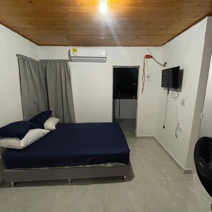 A bedroom with a bed, an air conditioner, a television, and a door leading to another room. - MIRADOR MTR LODGING (Montería)