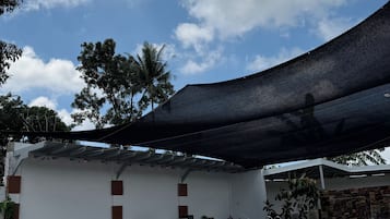 Un edificio de fachada blanca, un área de piscina con azulejos azules y una serie de escalones color beige que conducen a la piscina.