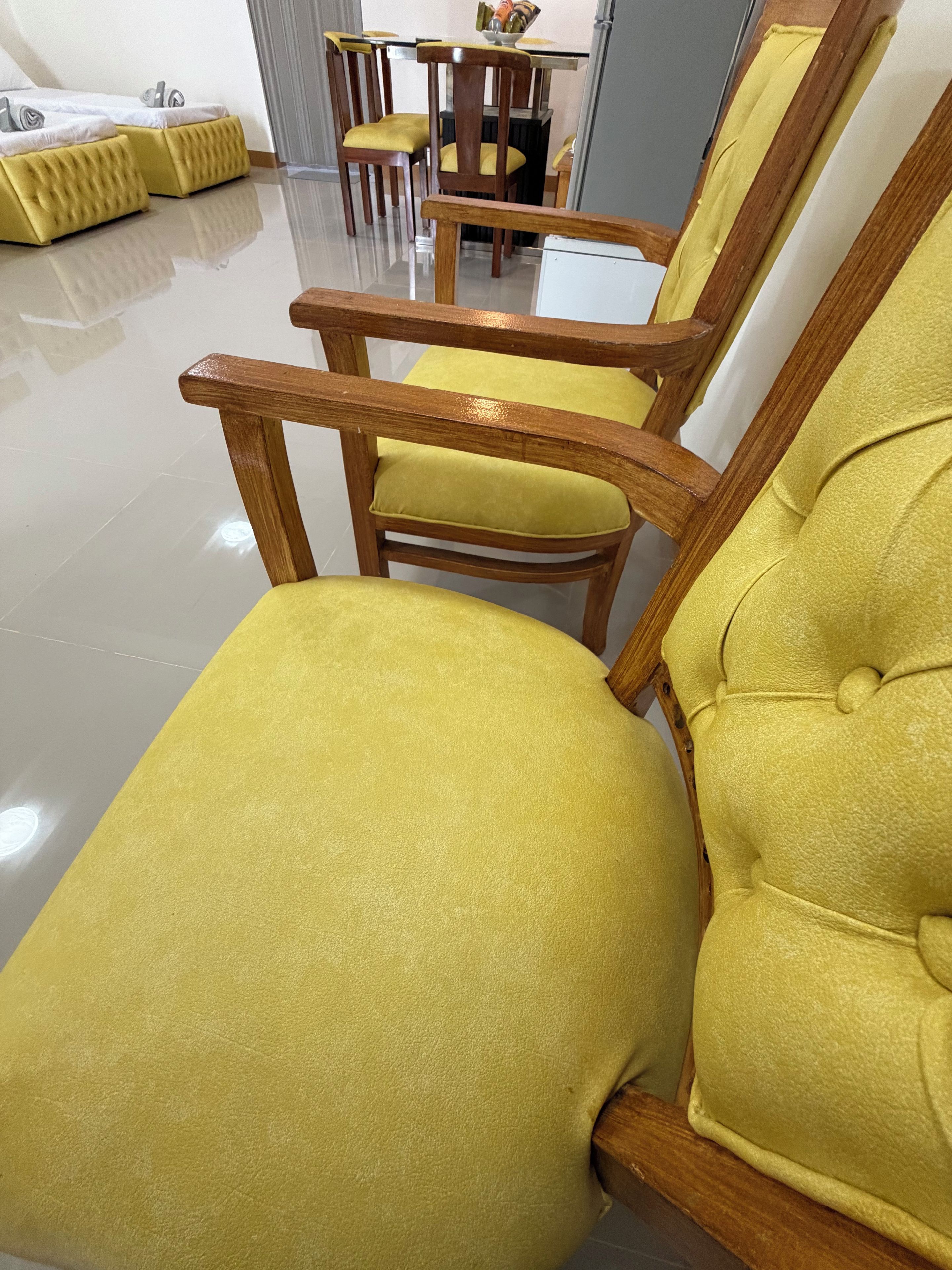 A room with yellow upholstered chairs and a wooden table with a bowl on it.