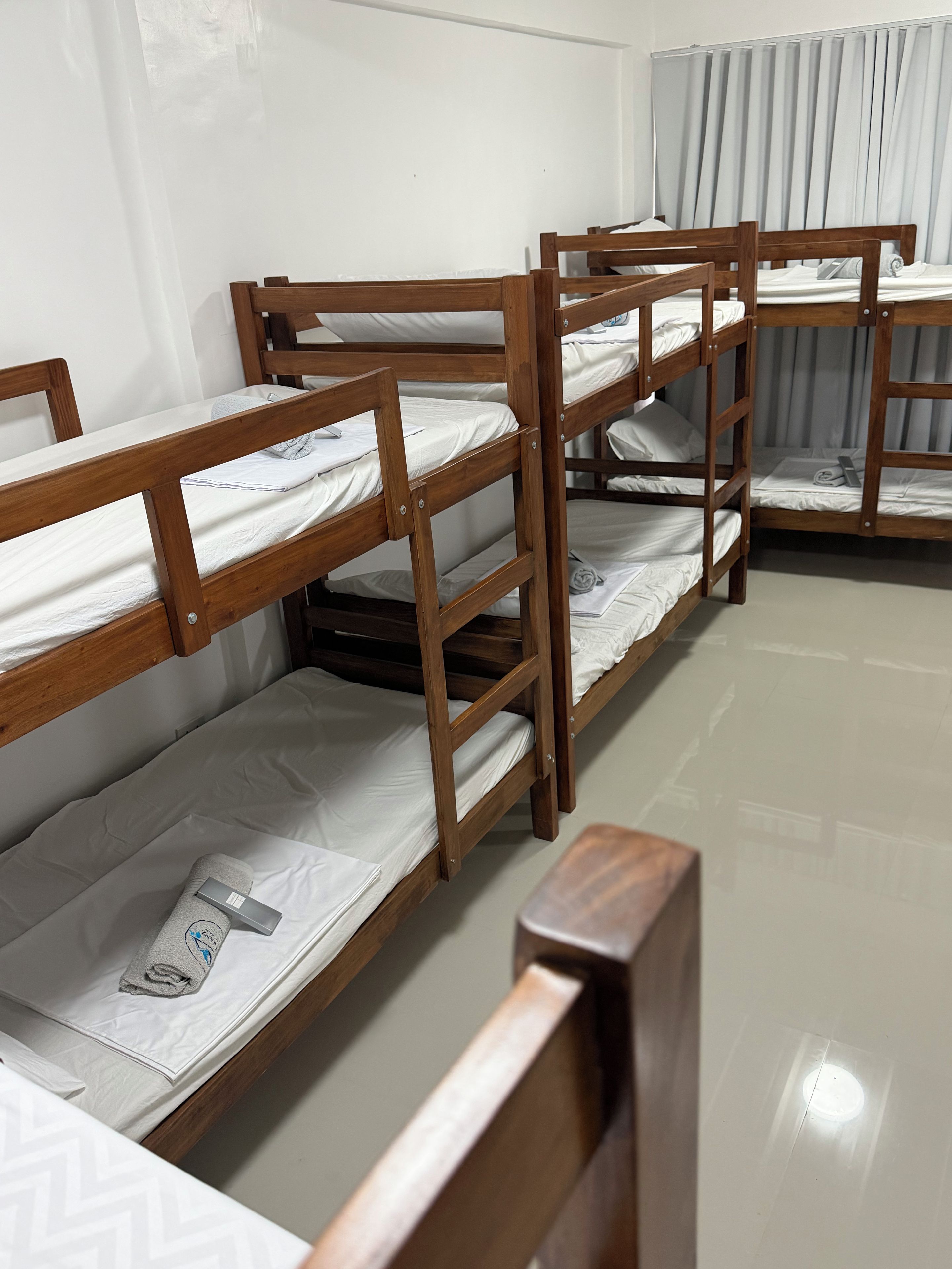 Bunk beds arranged in a row with white bedding and a grey pillow on each bed.