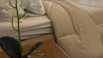 A hotel room with a bed, a heart-shaped towel arrangement, and a potted orchid.