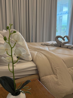 Habitació d'hotel amb un llit, una disposició de tovalloles en forma de cor i una orquídia en test.