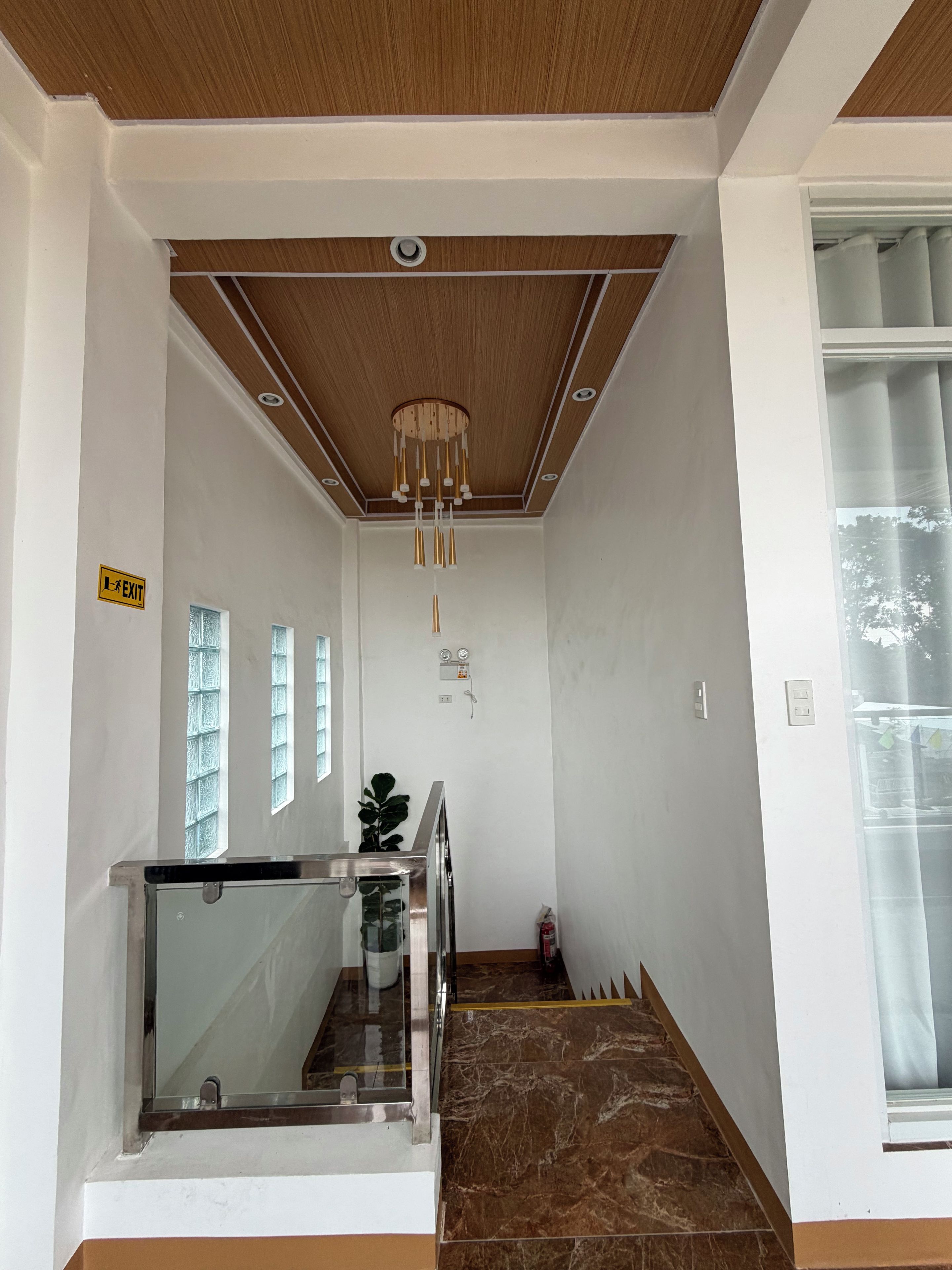A hallway with a wooden ceiling, a glass railing, and a marble floor.