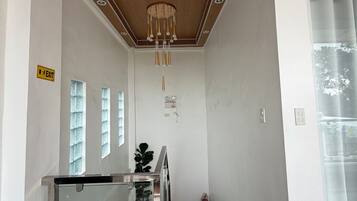 A hallway with a wooden ceiling, a glass railing, and a marble floor.