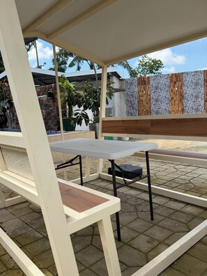 Un patio al aire libre con una mesa y sillas, rodeado por un muro de piedra y plantas en macetas.
