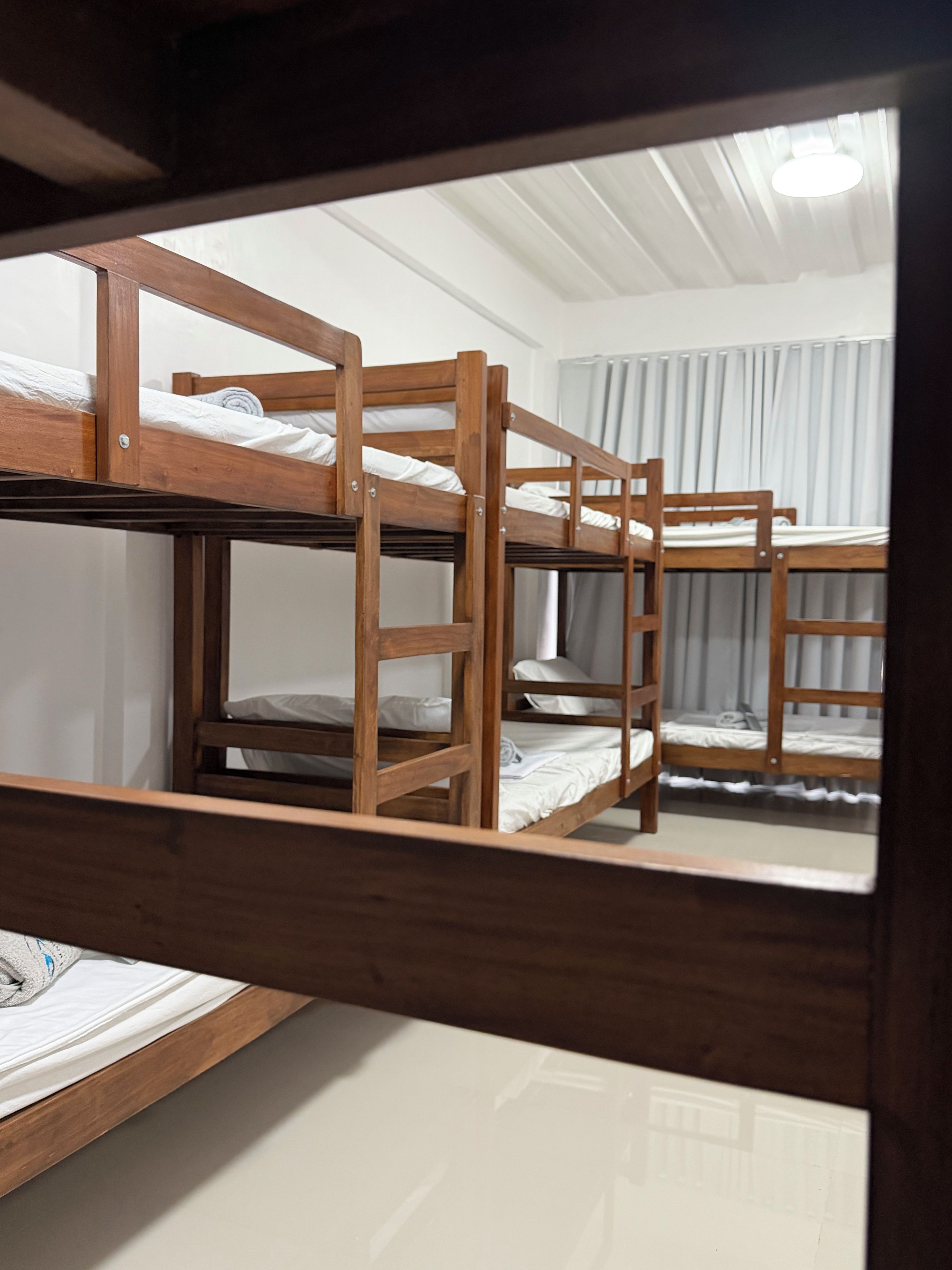 A bunk bed room with wooden frames, a ladder, and a curtain.