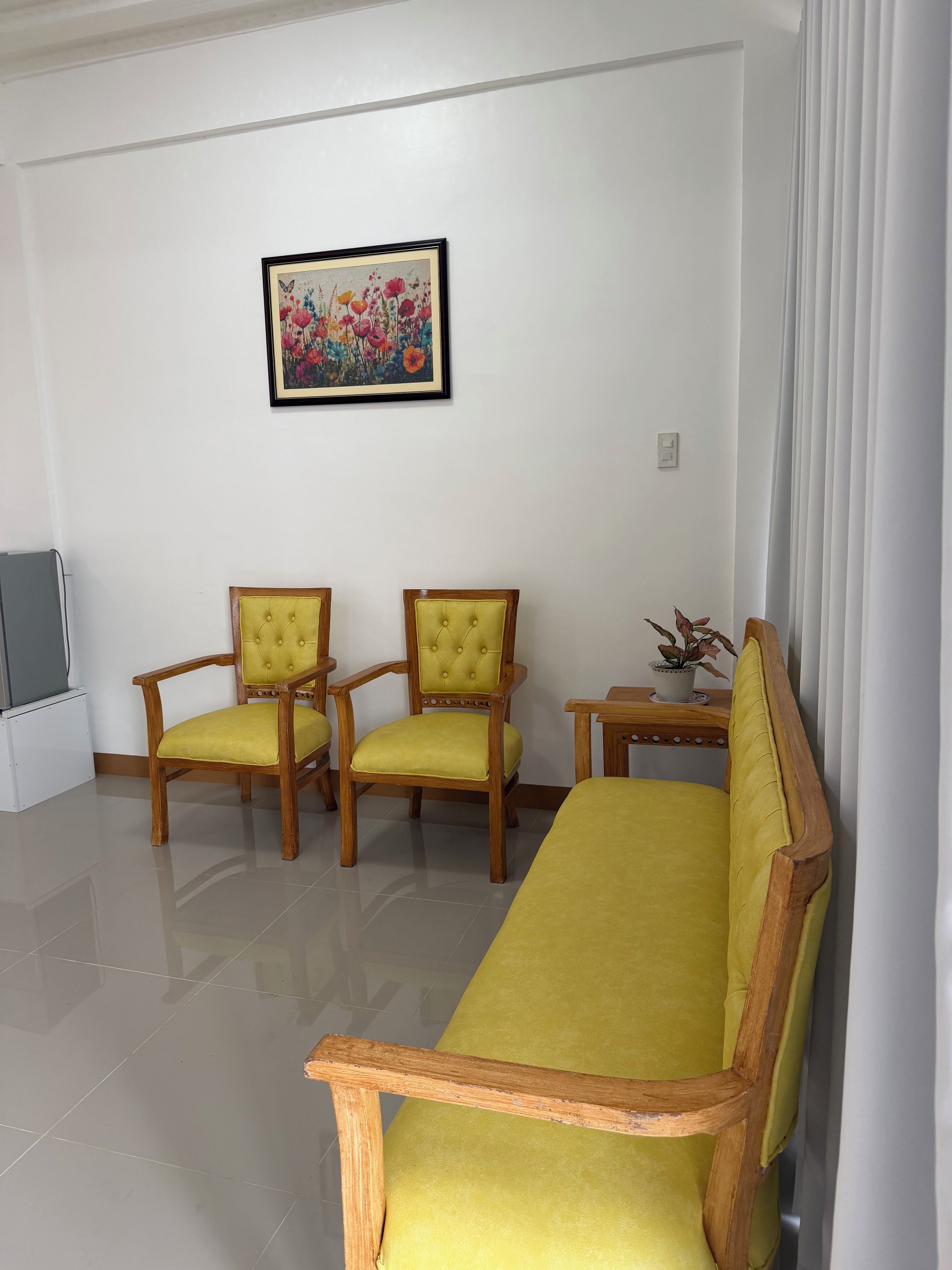 A living room with a sofa, two armchairs, a small table, and a painting on the wall.