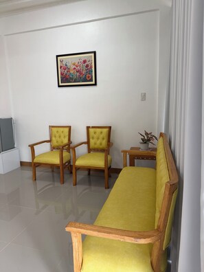 A living room with a sofa, two armchairs, a small table, and a painting on the wall.