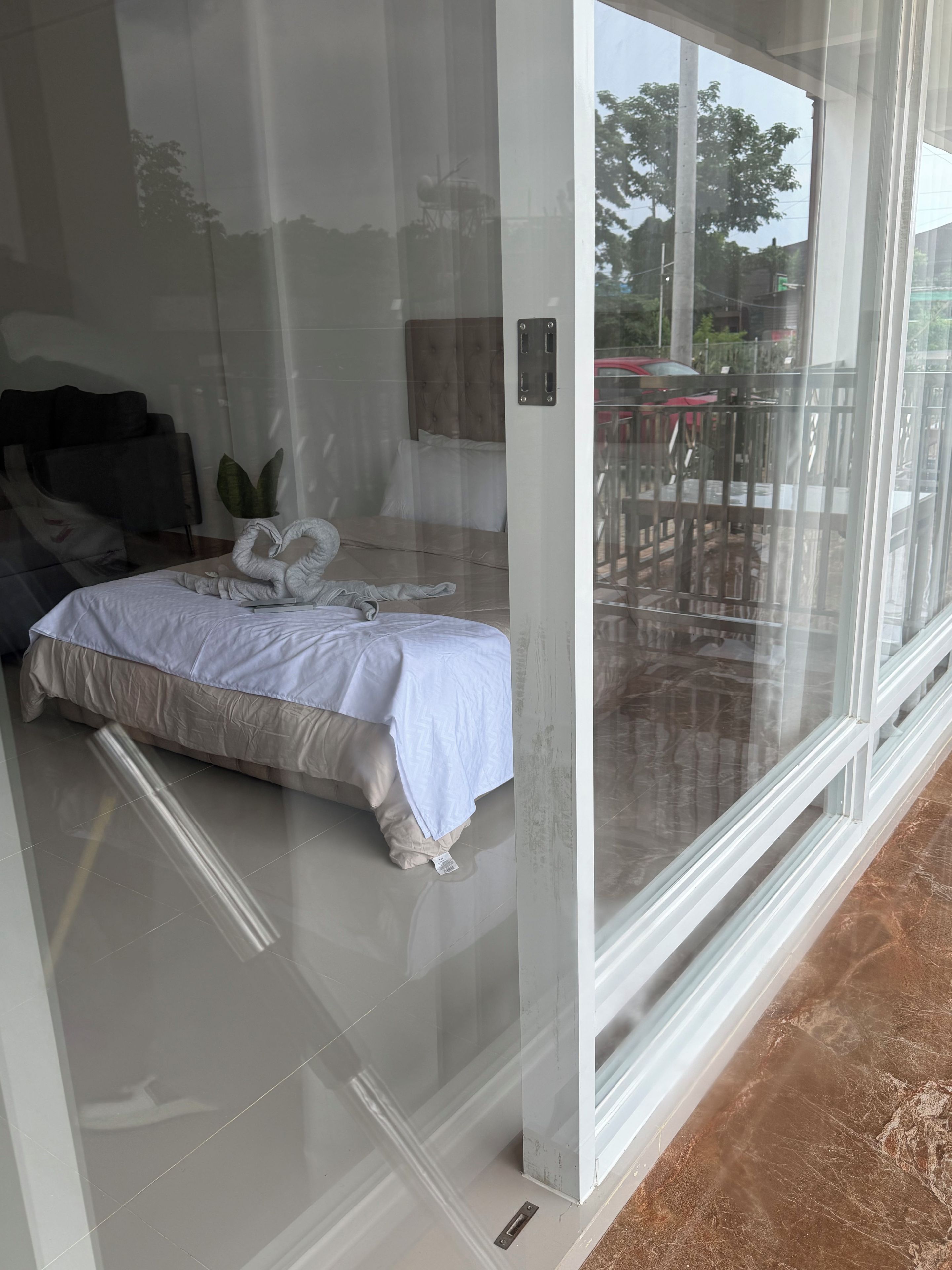 Una habitación con cama, una silla y un amplio ventanal que da a un espacio exterior.