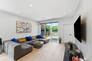 Ein modernes Wohnzimmer mit einer Eckcouch, einem Couchtisch und einem an der Wand befestigten Flachbildfernseher.