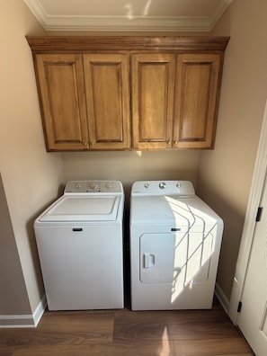 A laundry room with two white front-loading washing machines and wooden cabinets above.