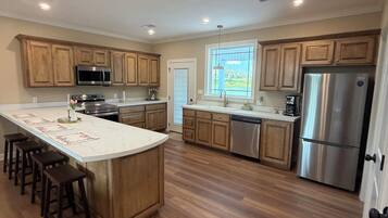 A modern kitchen with wooden cabinets, stainless steel appliances, and a central island with bar stools.